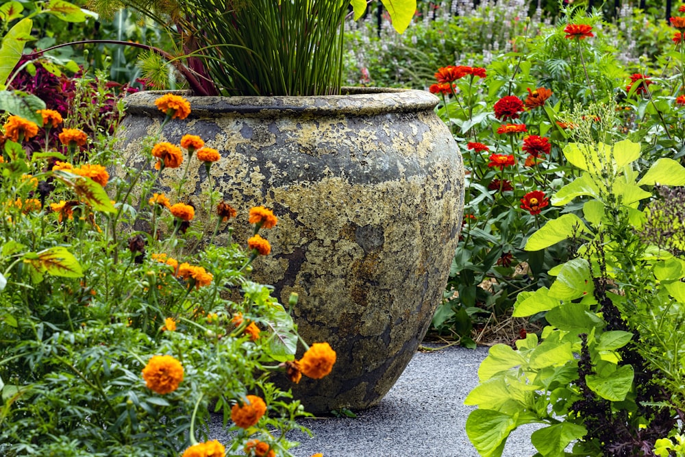 un gran jarrón sentado en medio de un jardín lleno de flores