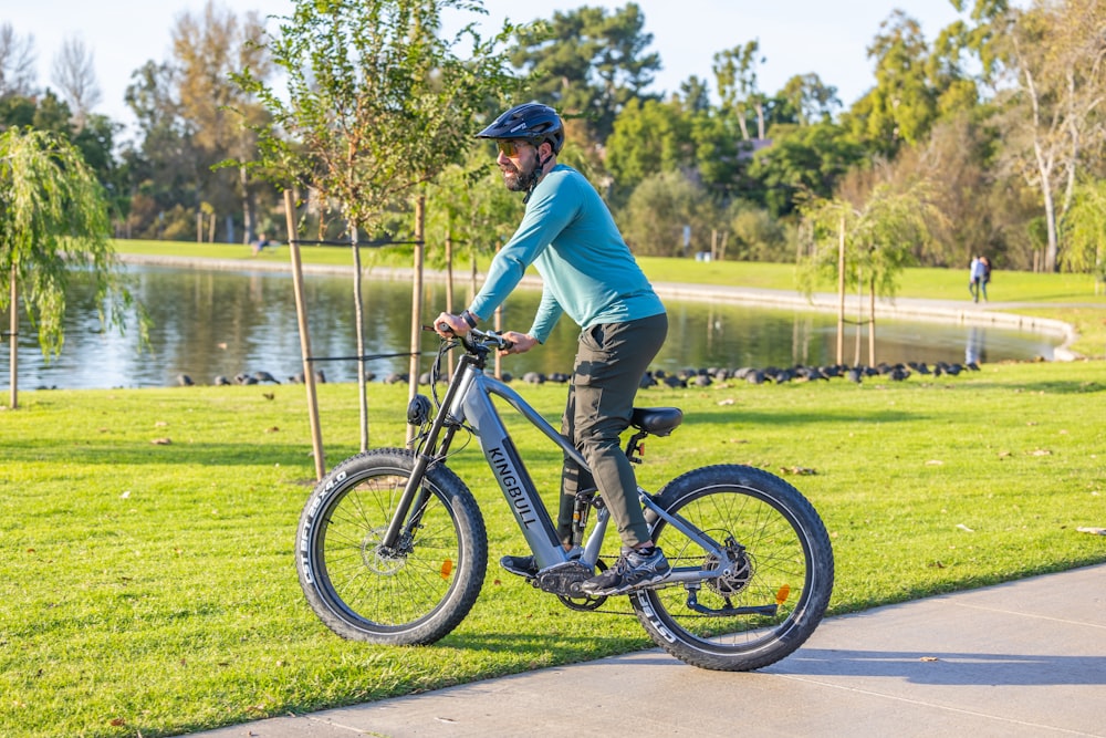 a man riding a bike down a sidewalk next to a lake