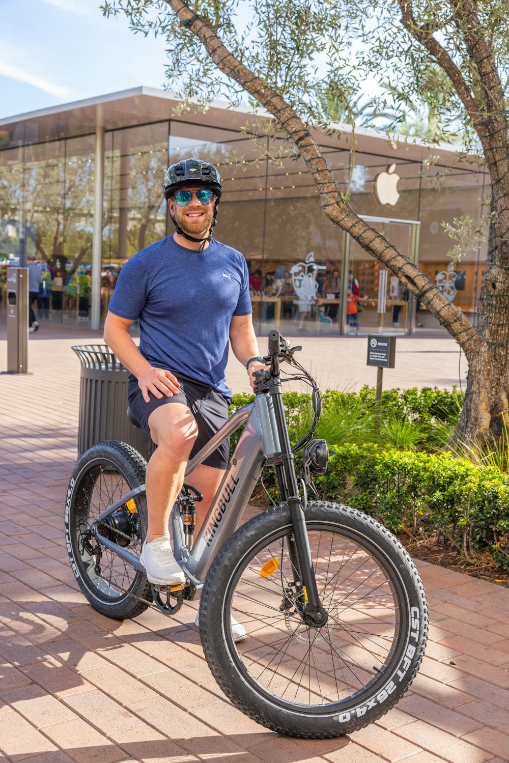 a man sitting on top of a bike next to a tree