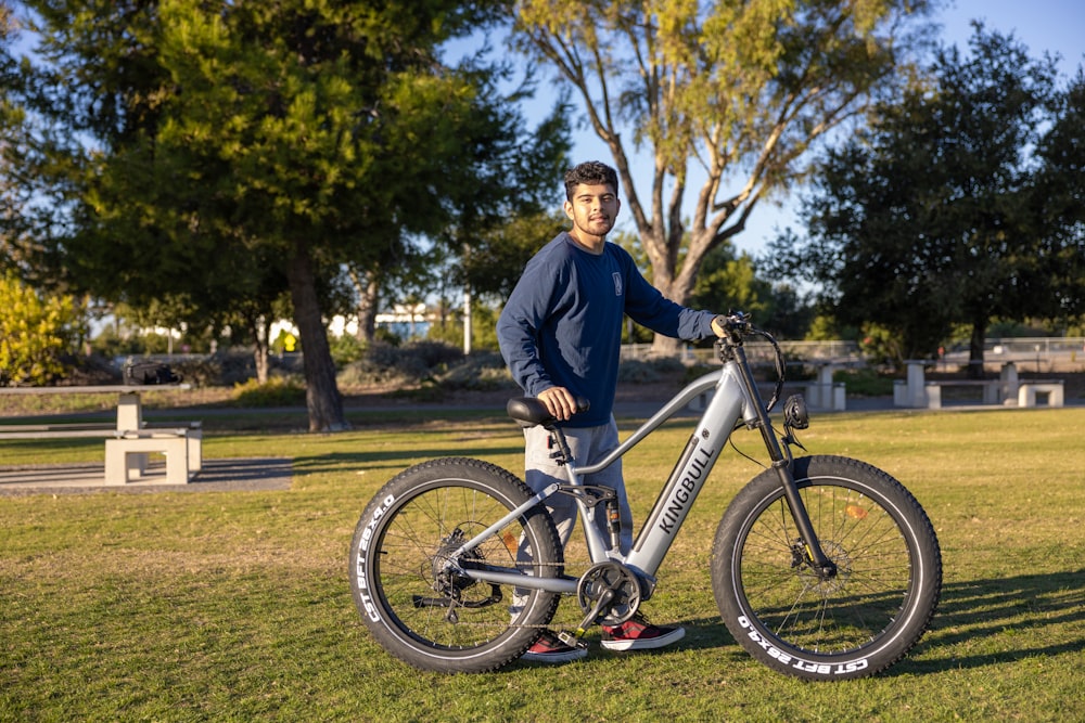 a man standing next to a bike in a park