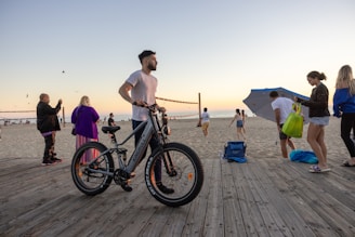 A friendly guide helping a family prepare their e-bikes by the coast at sunset.