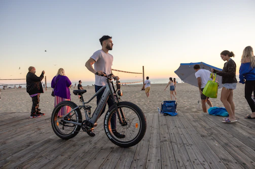 A group of friends riding colorful exploit e bikes along a coastal boardwalk, laughter in the air.