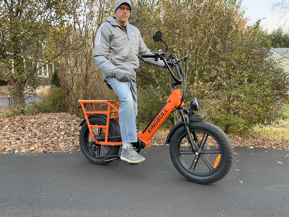 a man is sitting on an orange bike