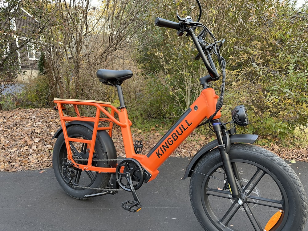 an orange electric bike parked on the side of a road