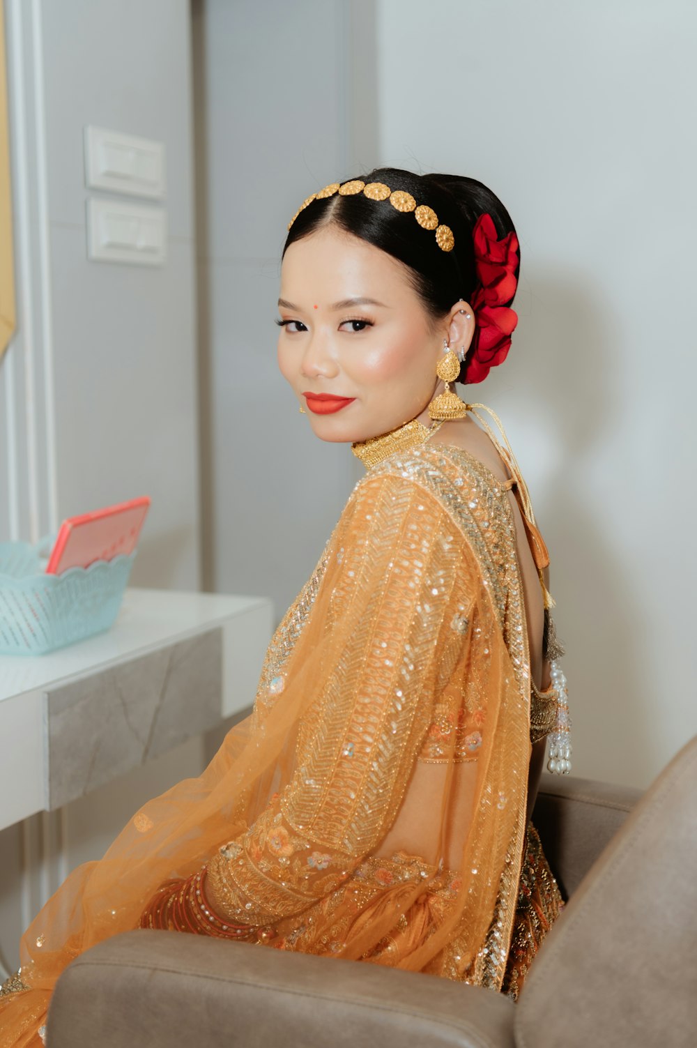 a woman sitting on a chair with a red flower in her hair