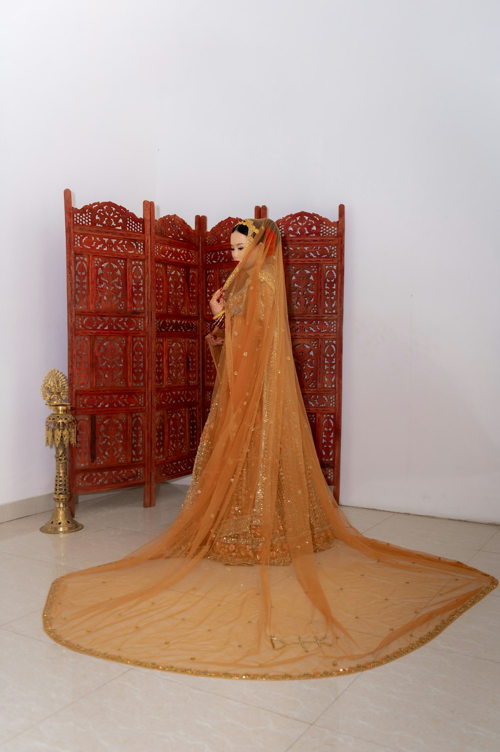 a woman in a bridal veil standing in front of a red screen