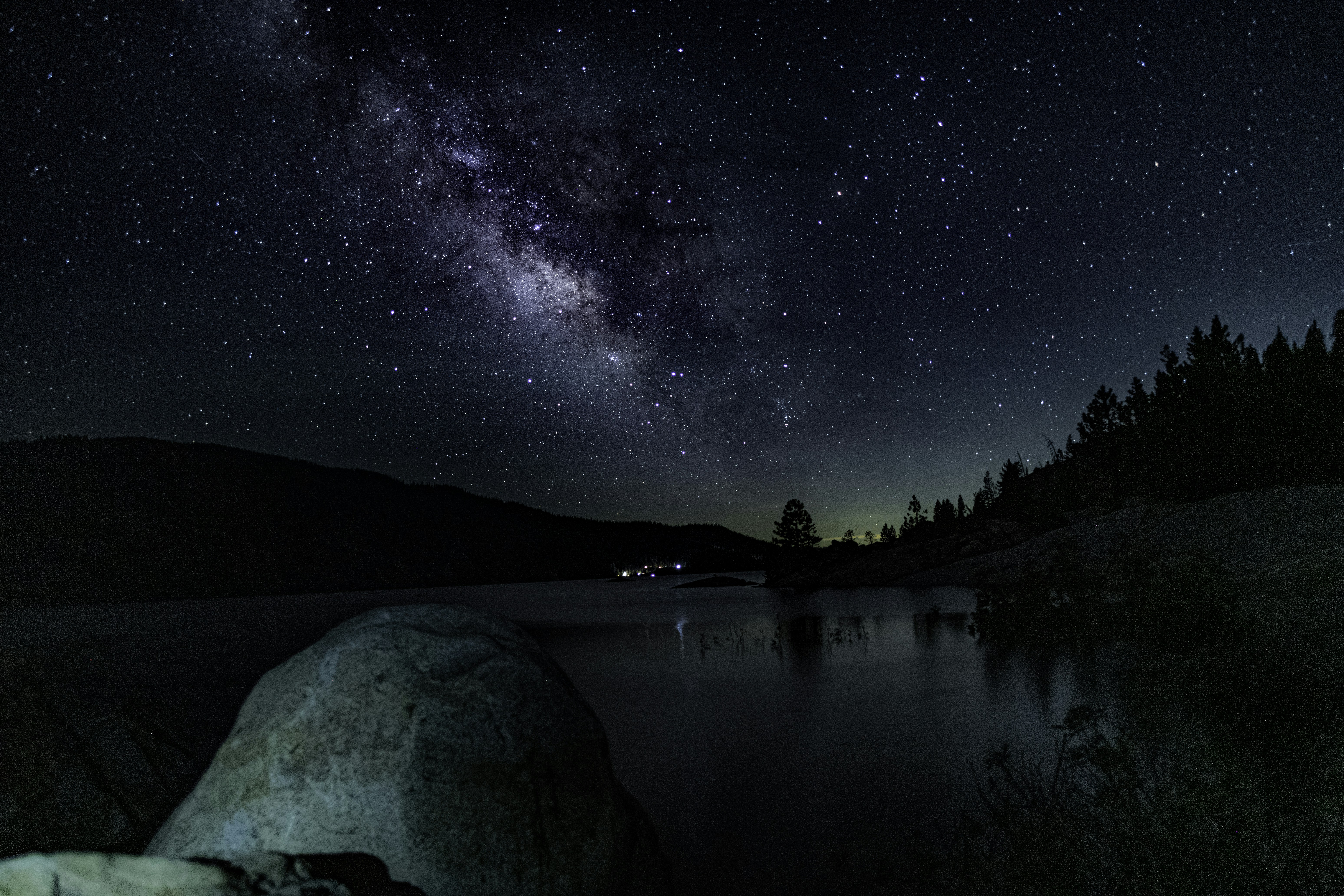 the night sky is filled with stars above a lake