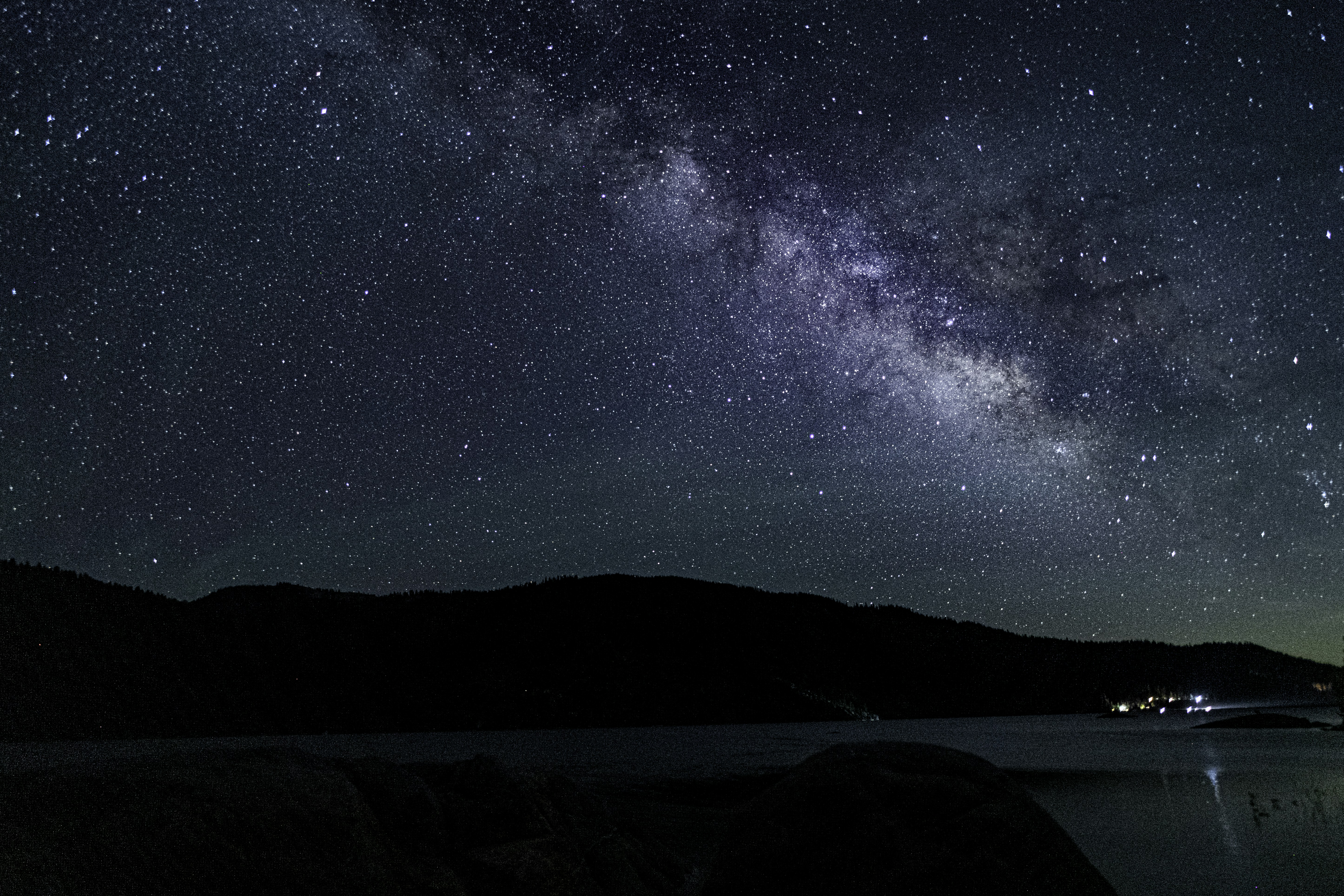 the night sky is filled with stars above a body of water