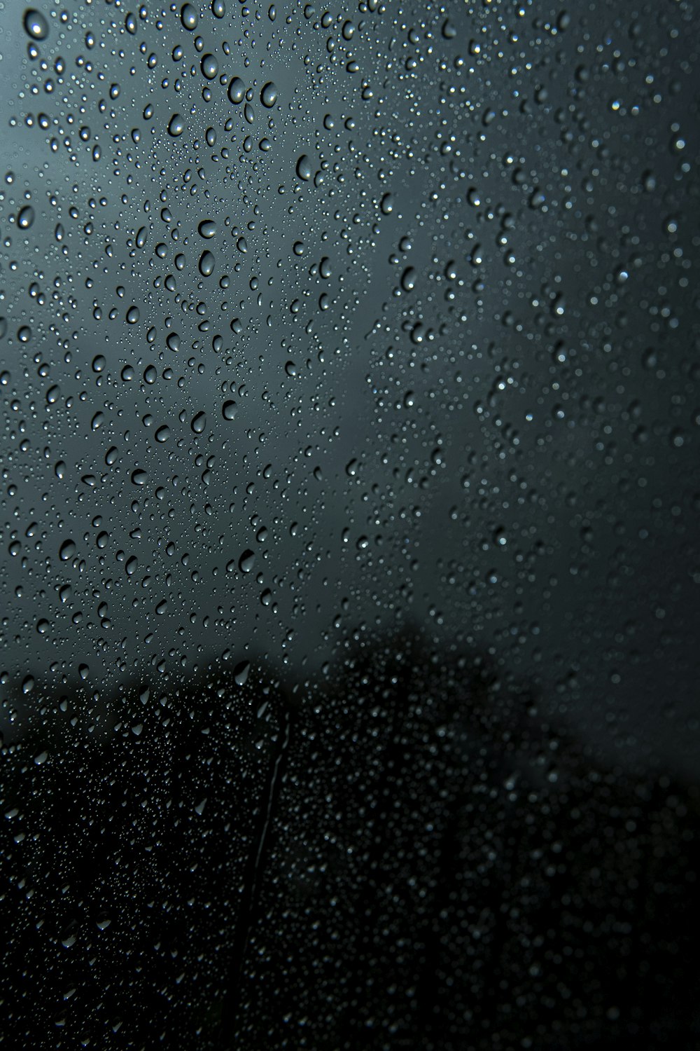 rain drops on a window with a dark sky in the background