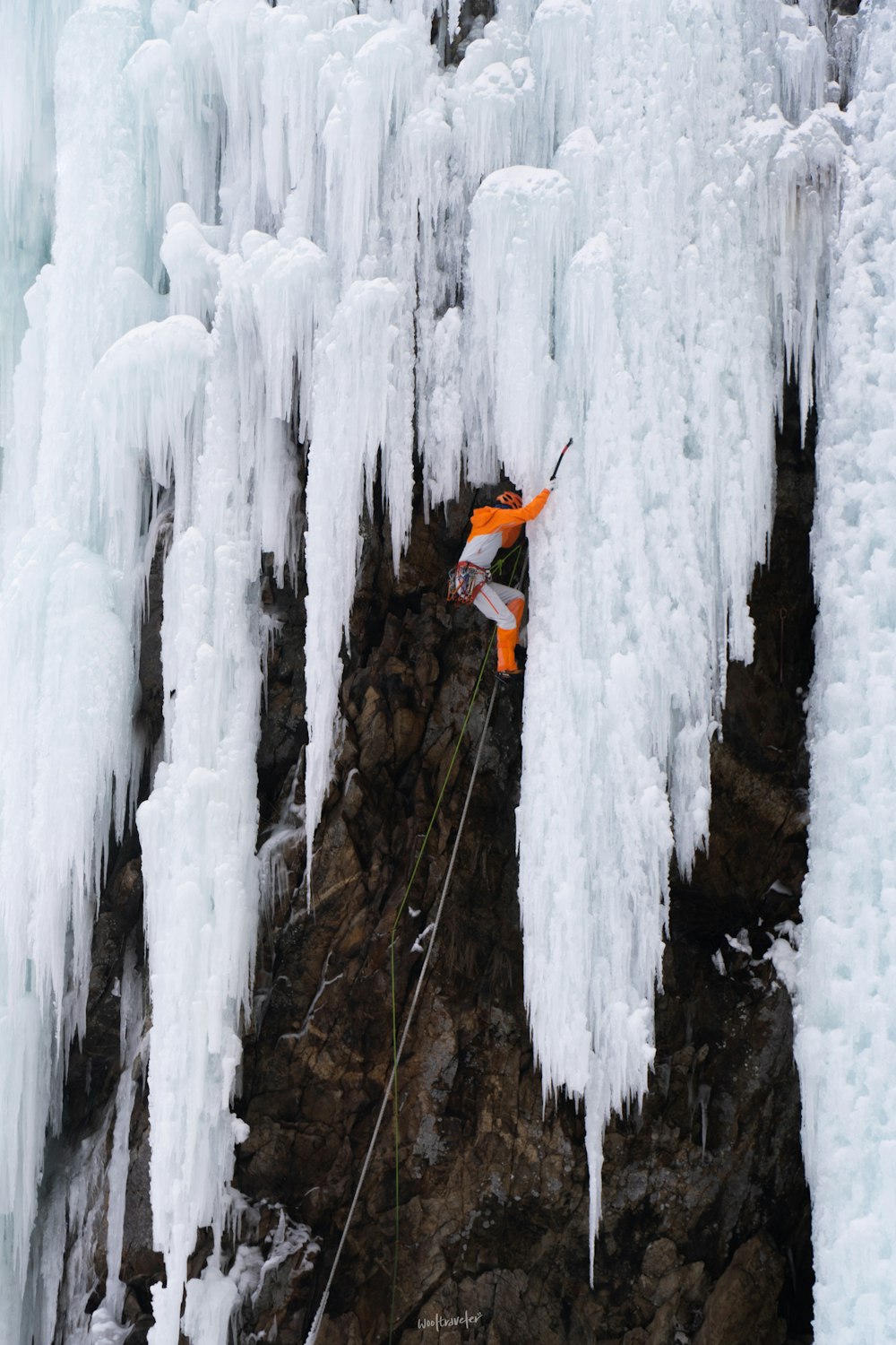 a man climbing up the side of a mountain covered in ice