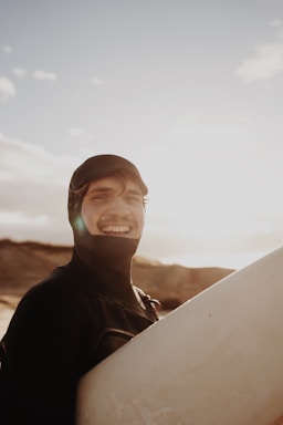 Smiling surfing instructor helping a beginner with a surfboard on Legian beach at sunset.