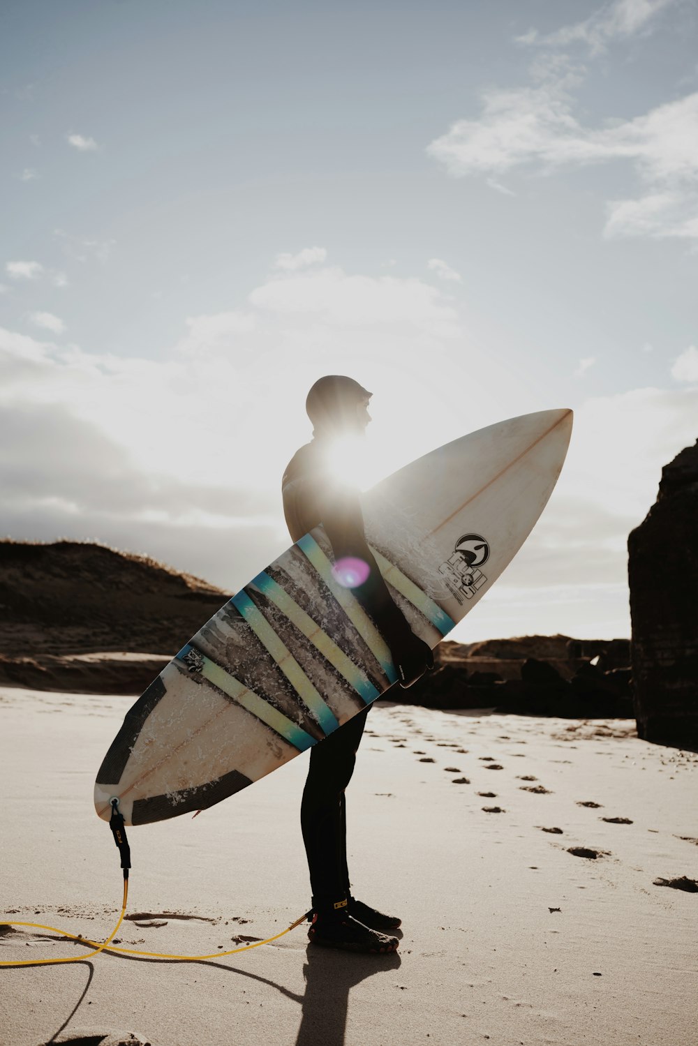 Ein Mann hält ein Surfbrett auf einem Sandstrand