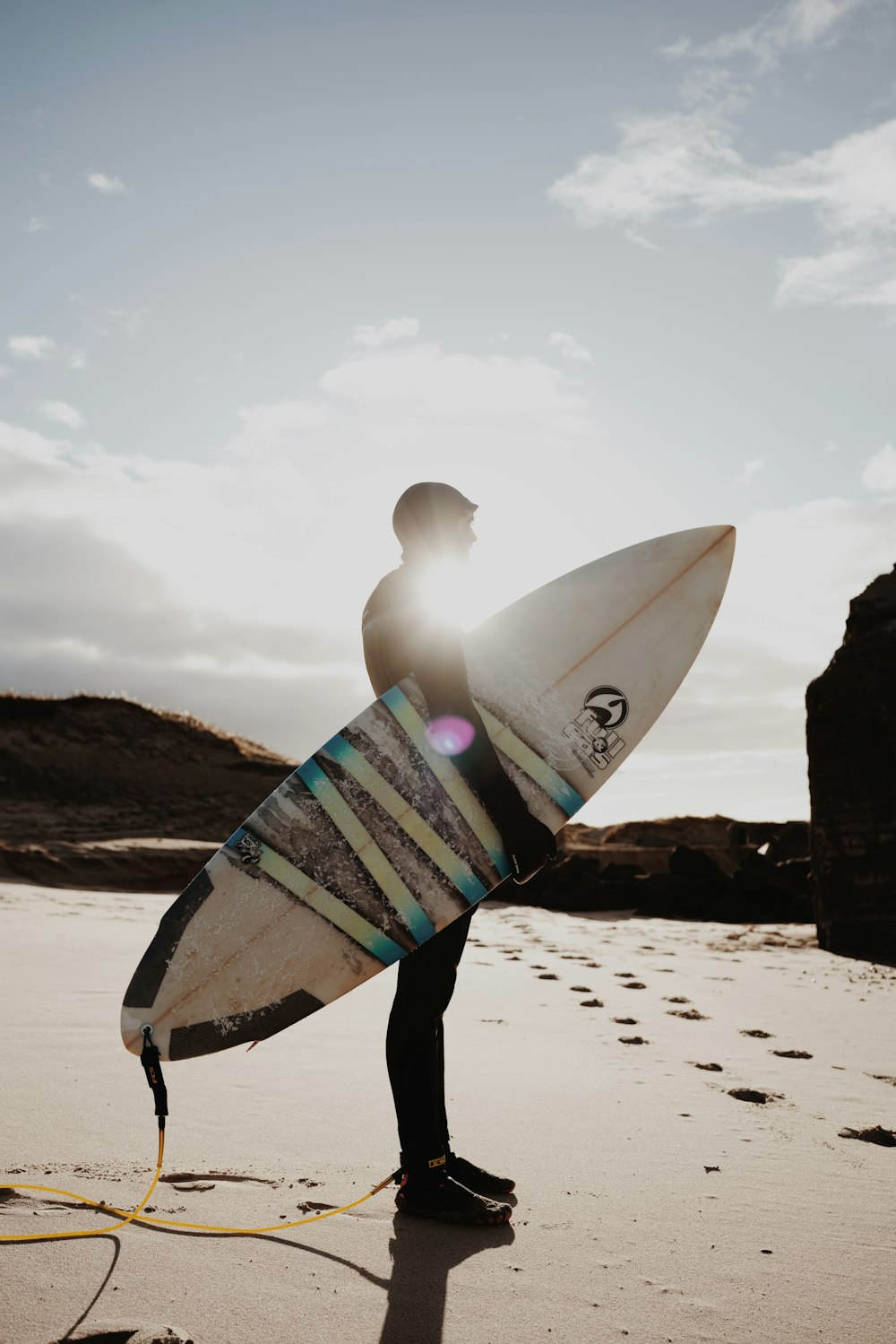 a man holding a surfboard on top of a sandy beach