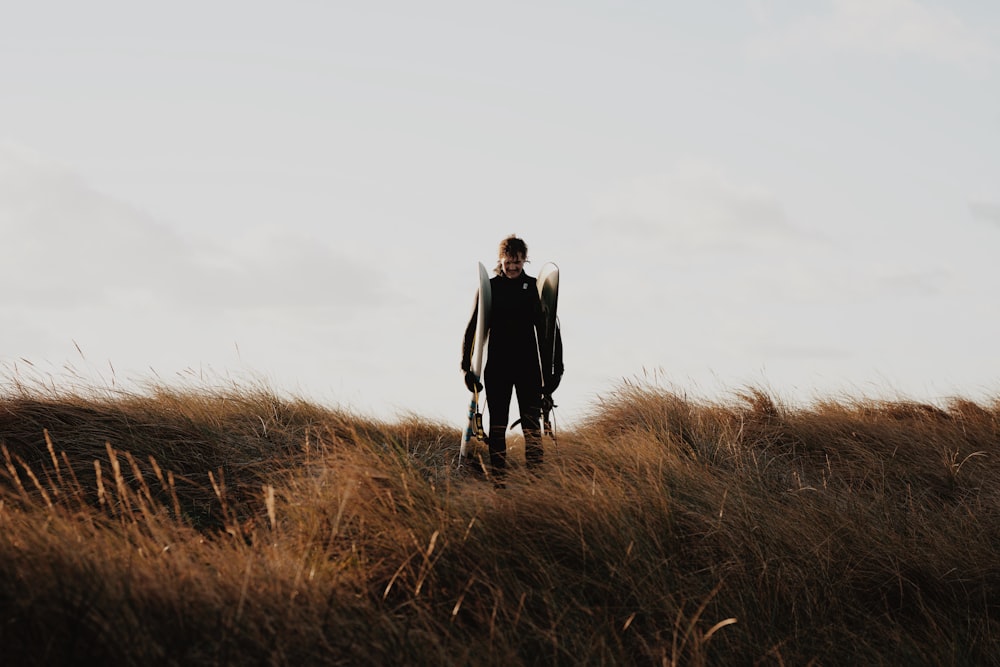 a man standing on top of a grass covered hillside