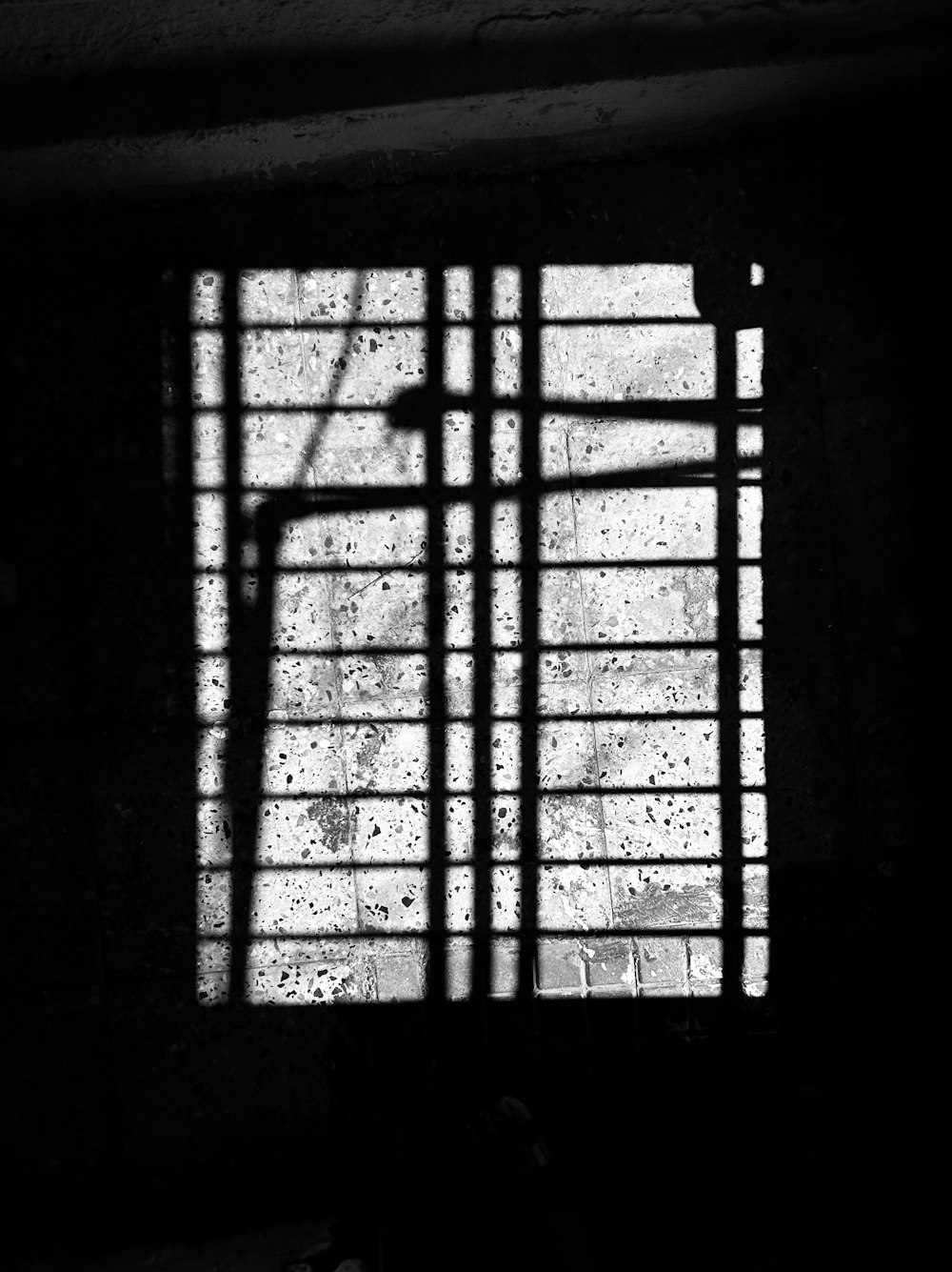 uma foto em preto e branco de uma janela com barras