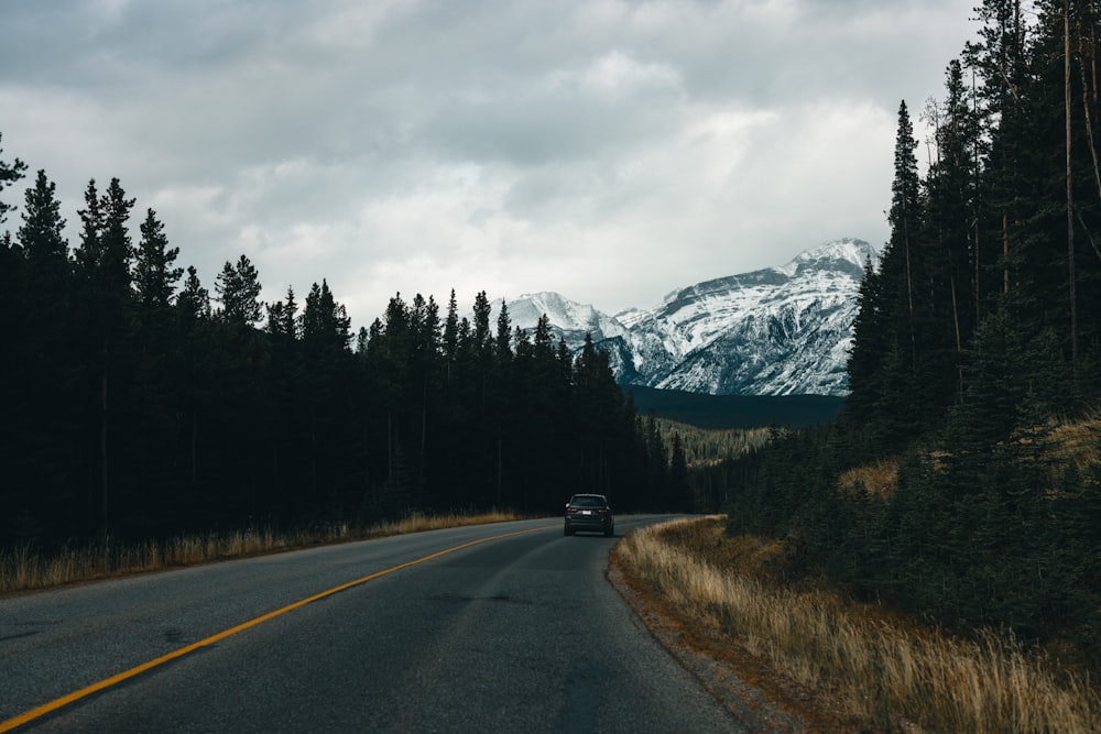 a car driving down a road with a mountain in the background