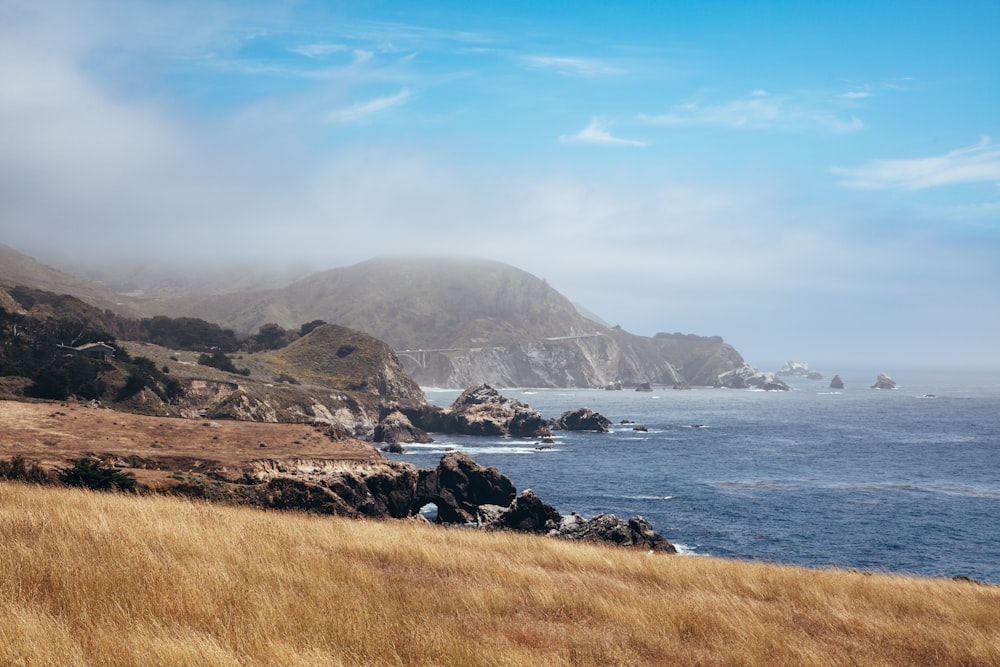 a grassy hill with a body of water in the background