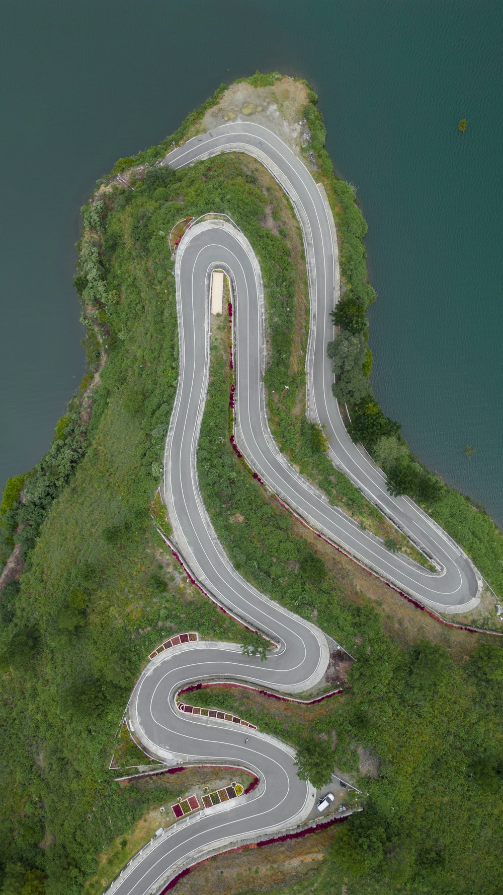 an aerial view of a winding road next to a body of water