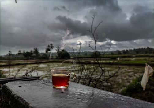 A steaming cup of tea set against a backdrop of rolling hills.