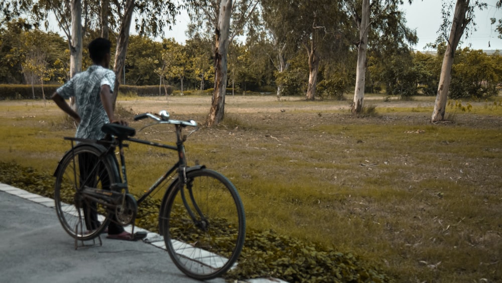 a man standing next to a bike on a road