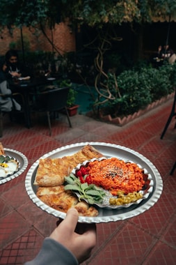 a person holding a plate of food on a table