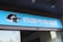 A building entrance features a vibrant blue sign with white Chinese characters and a stylized orca logo in black and white. The overall appearance suggests an establishment focused on eSports or digital activities.