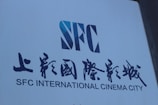 A large sign with bold text displays the letters 'SFC' in a stylized design, accompanied by both English and Chinese writing reading 'SFC INTERNATIONAL CINEMA CITY.' The sign is set against a plain background.