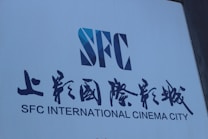 A large sign with bold text displays the letters 'SFC' in a stylized design, accompanied by both English and Chinese writing reading 'SFC INTERNATIONAL CINEMA CITY.' The sign is set against a plain background.