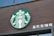 A circular logo featuring a stylized mermaid with two tails, placed on a dark brown wooden wall. To the right, there are Chinese characters in white.