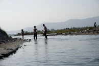 Wide shot of a clean river with team members conducting water quality tests.