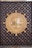 An ornate door features a prominent circular design in the center, with intricate Arabic calligraphy surrounded by geometric patterns. The wood is rich and dark, with metal accents and a golden-hued centerpiece showcasing elaborate detailing.