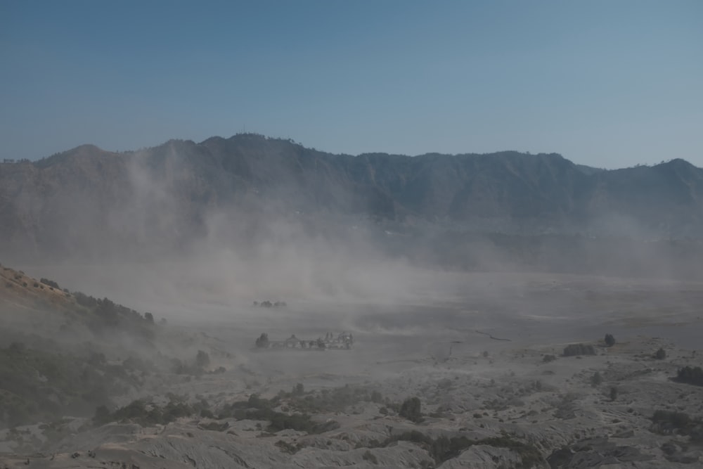 a foggy landscape with mountains in the distance