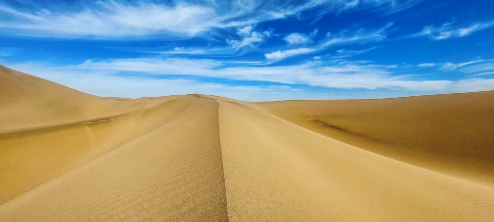 a large sand dune with a blue sky in the background