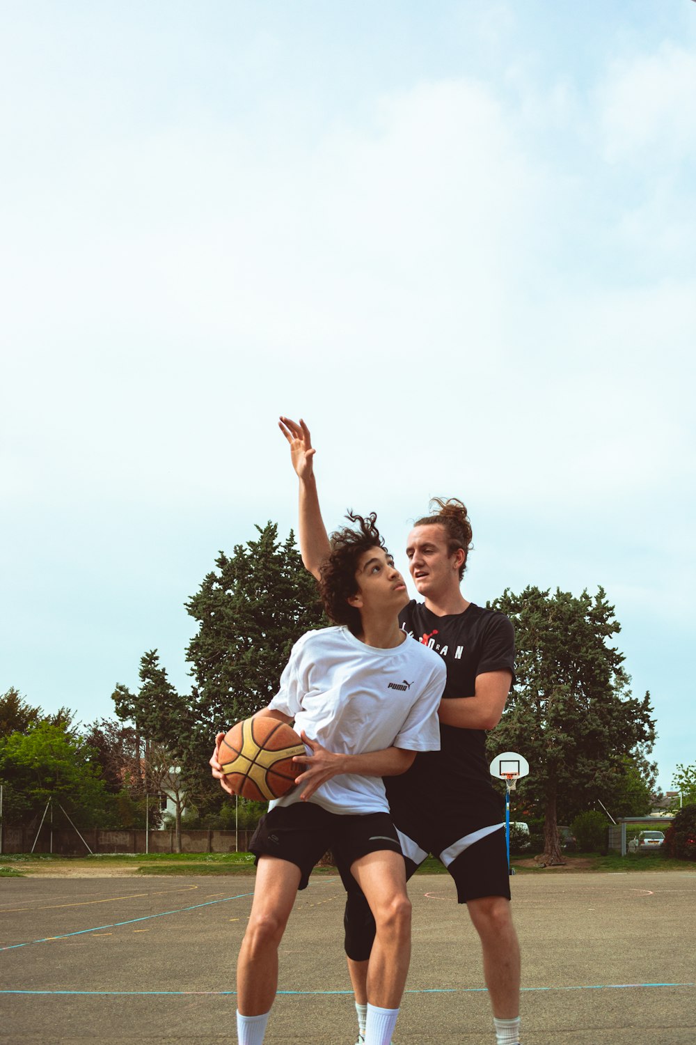 a couple of men standing on top of a basketball court