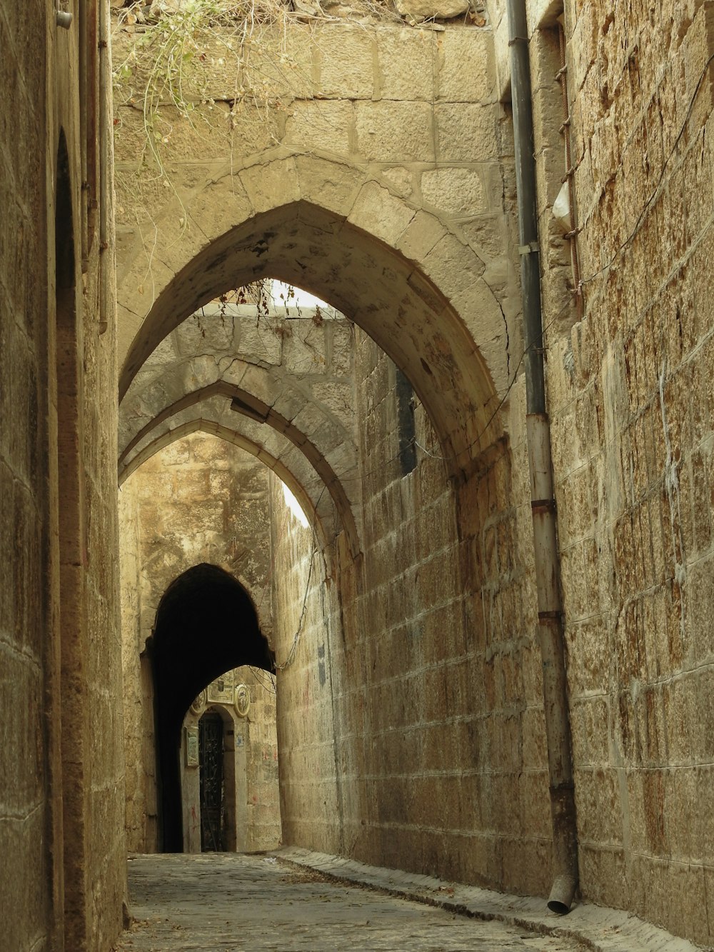 a narrow alley way with stone walls and arches
