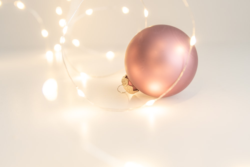 a pink ornament with a string of lights around it