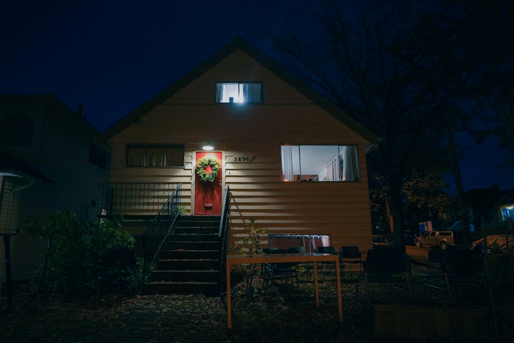 a house lit up at night with a wreath on the door