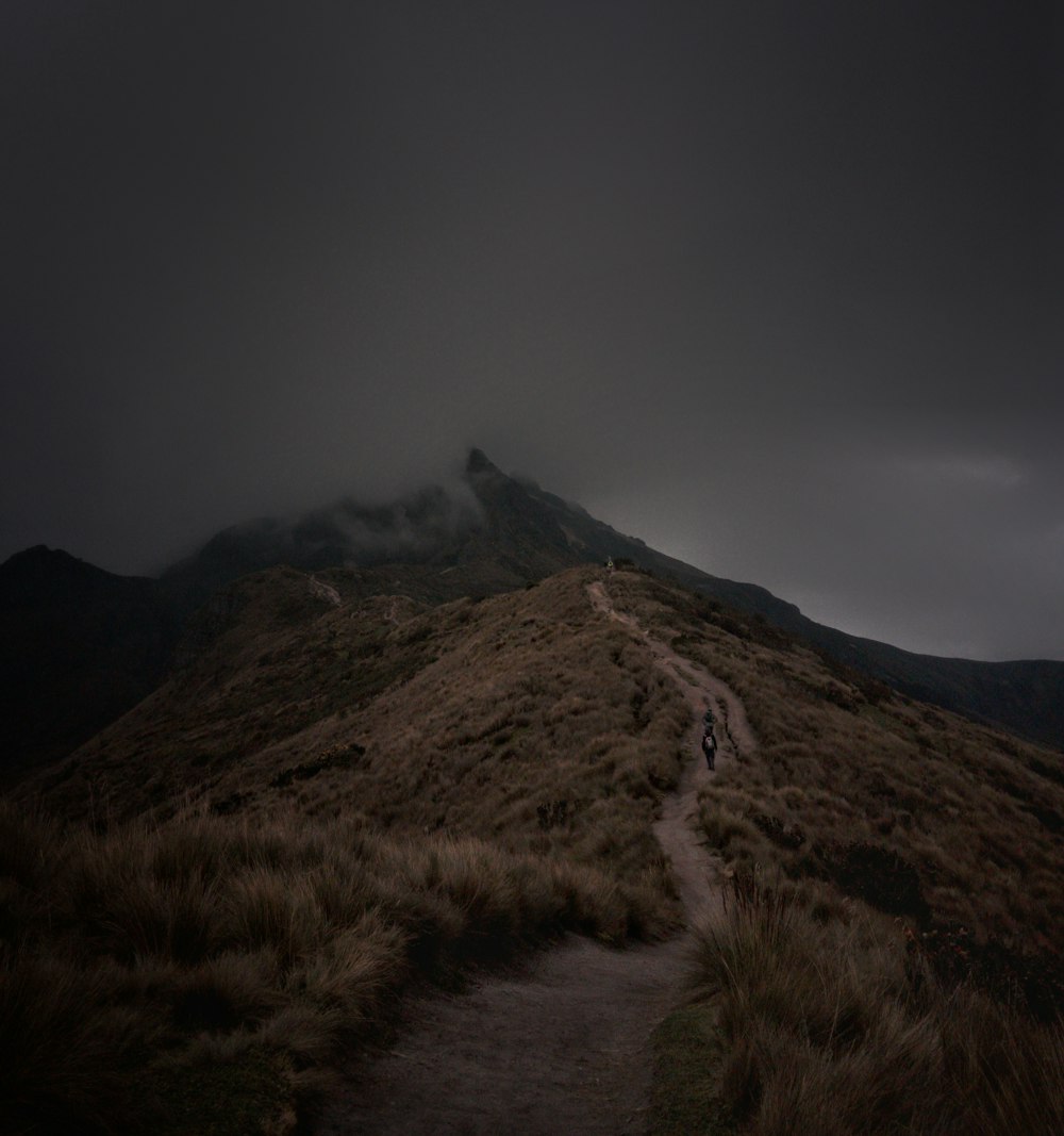 a path leading up a hill with a dark sky in the background