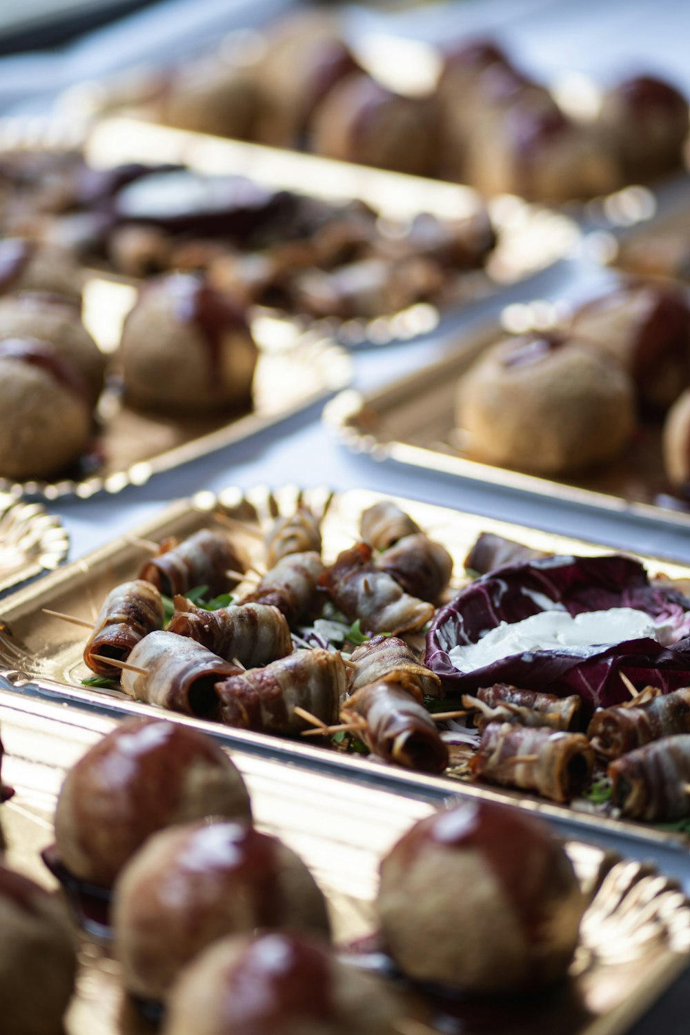 a table topped with trays of food covered in meatballs