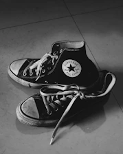 Close-up of classic All Star sneakers on a wooden floor with soft natural light.