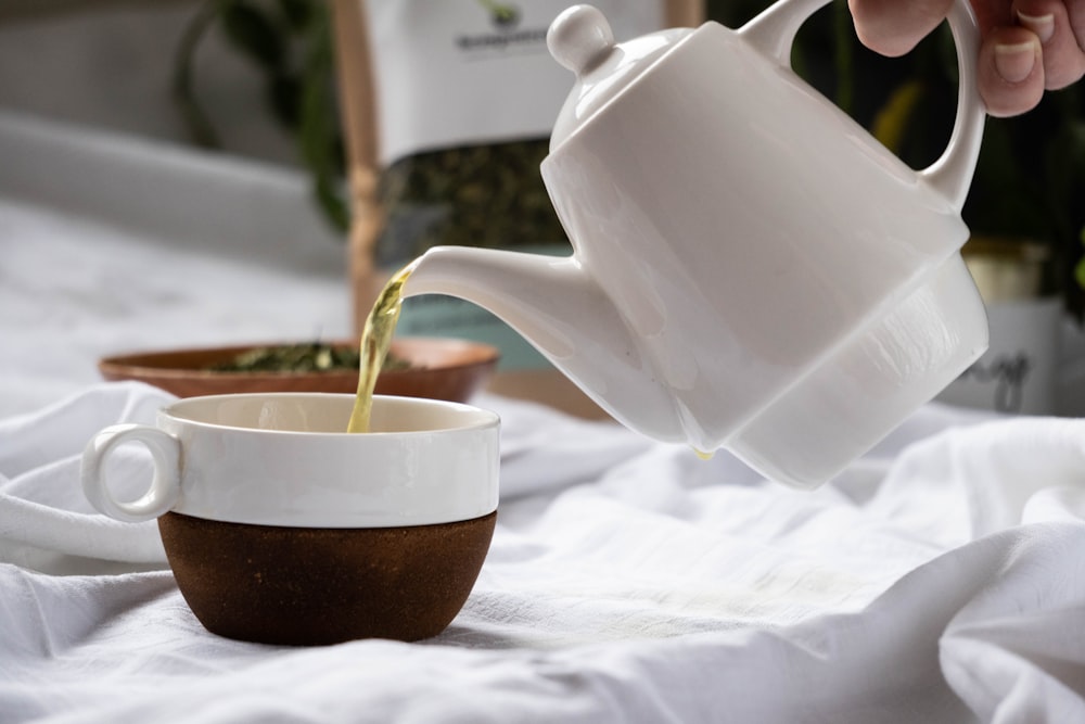 a person pouring tea into a cup on a bed