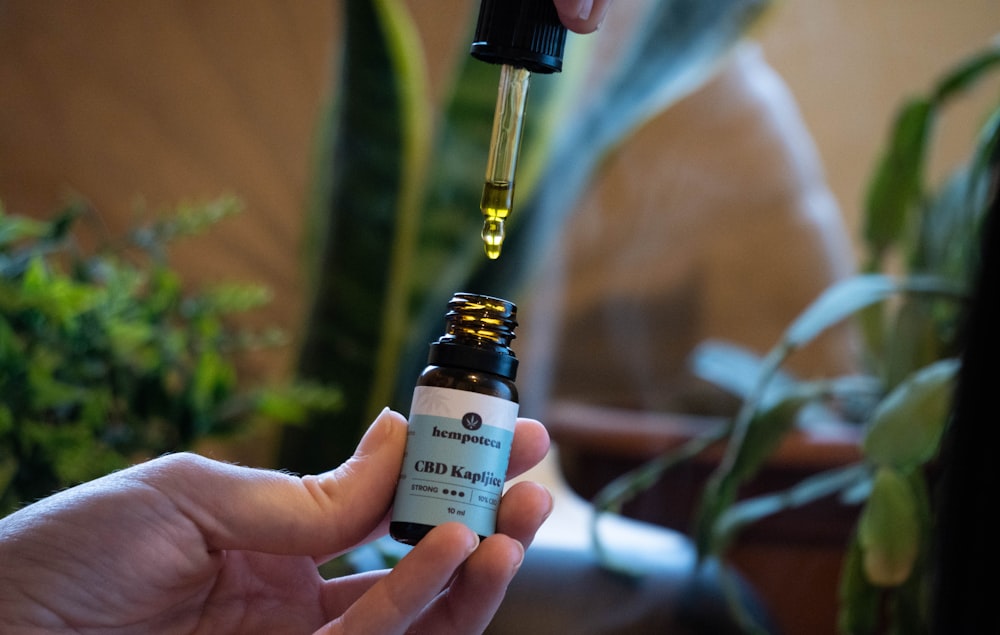 a person holding a bottle of essential oil