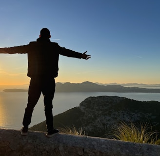a man standing on top of a cliff next to a body of water