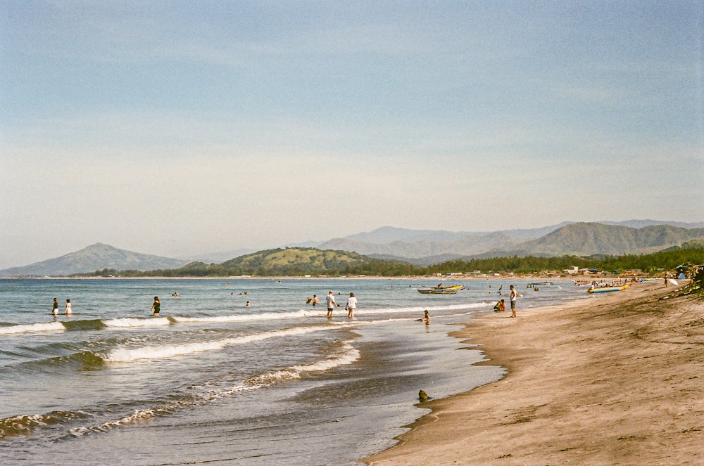 a group of people standing on top of a sandy beach