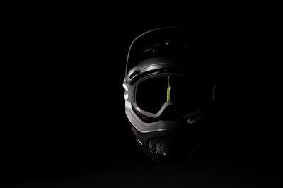 Sleek motorcycle goggles with reflective lenses placed on a dark metallic background