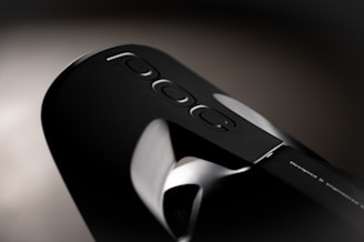 Close-up of a sleek, black modern device with a minimalist design that displays the word 'Poc' along with three small oval-shaped buttons. The device has a smooth, glossy surface with subtle metallic accents.