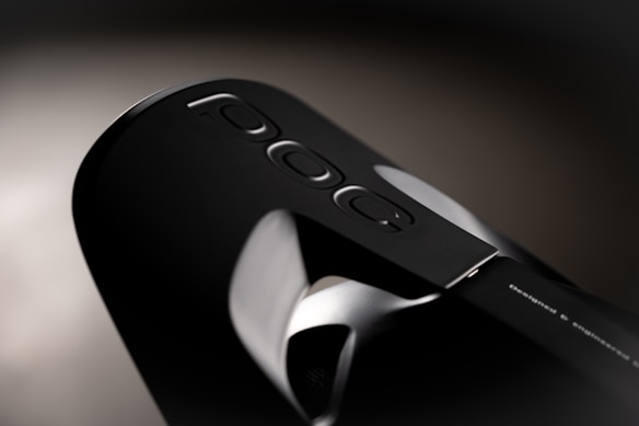 Close-up of a sleek, black modern device with a minimalist design that displays the word 'Poc' along with three small oval-shaped buttons. The device has a smooth, glossy surface with subtle metallic accents.