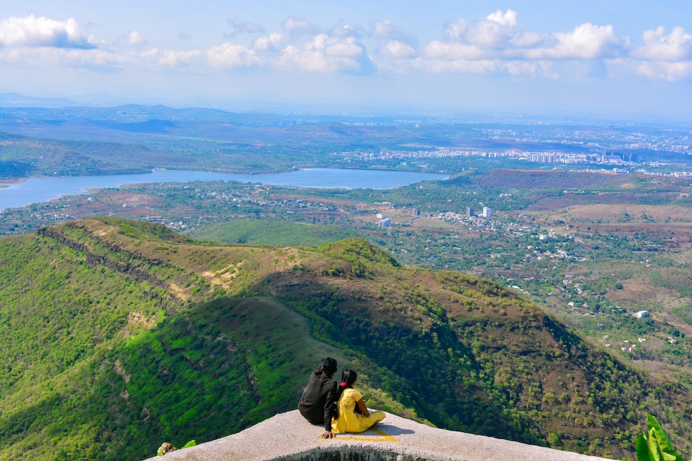 a couple of people sitting on top of a mountain