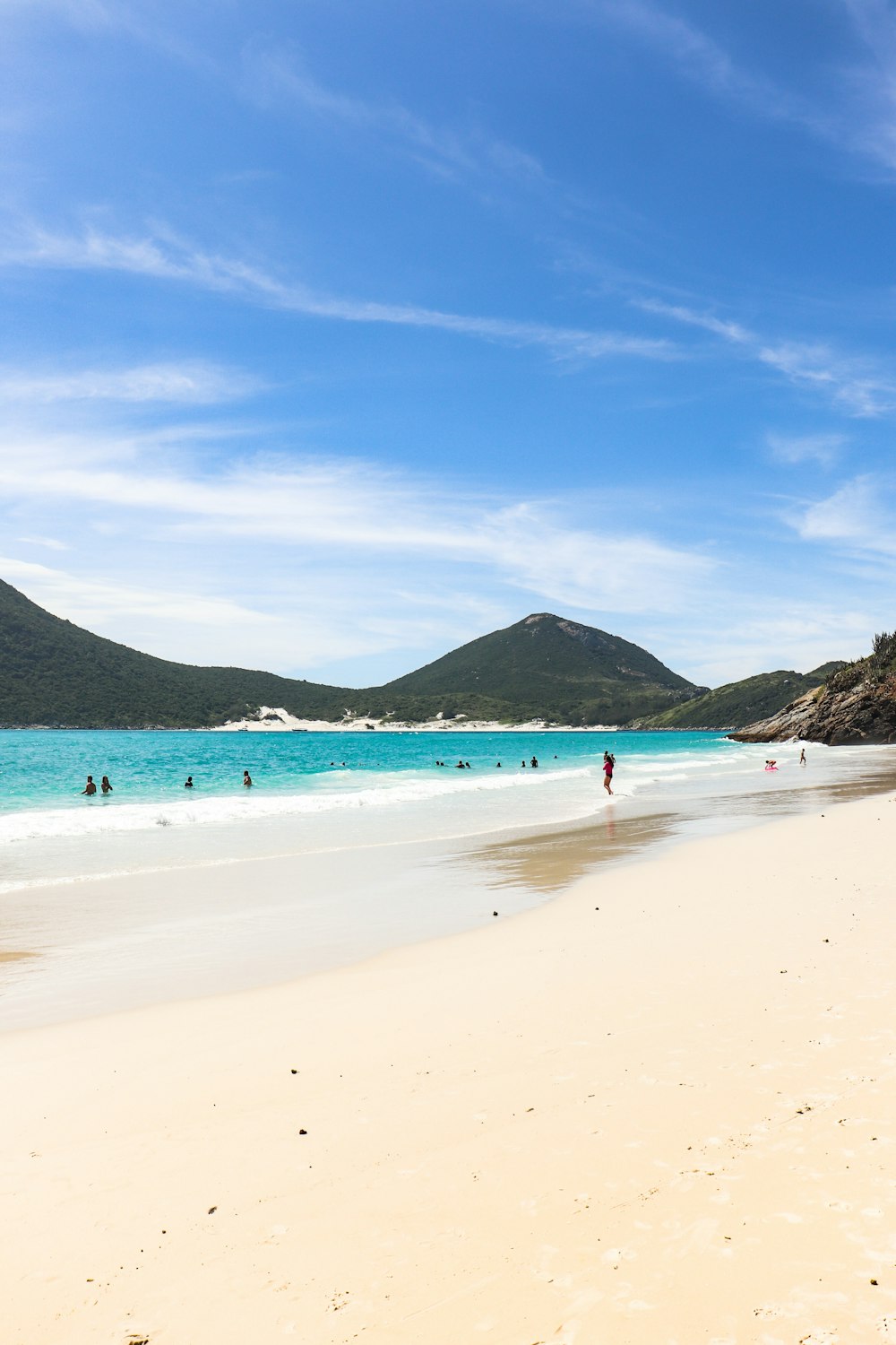 a sandy beach with people swimming in the water