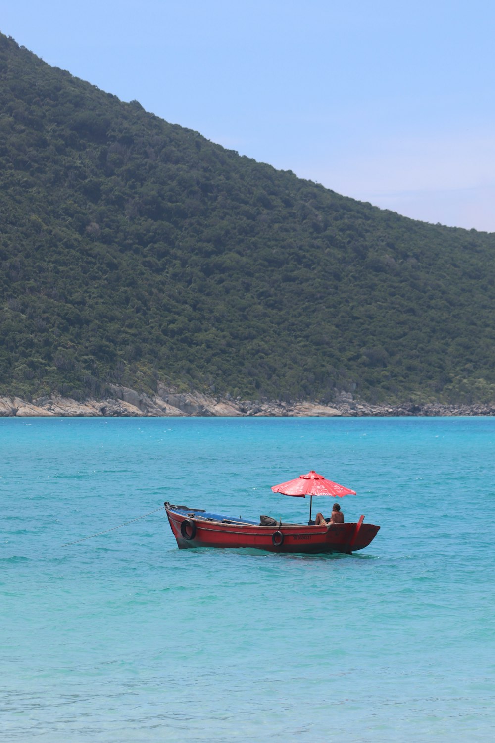 a red boat with a red umbrella in the water